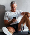 Man sitting on the floor looking at his Hume app with a water bottle beside him